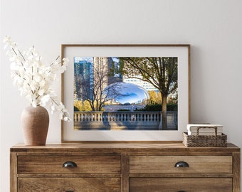 May include: A framed photograph of a modern, reflective sculpture in a city park. The sculpture is a large, silver, rounded shape, reflecting the surrounding buildings and sky. Trees and a stone fence are visible in the foreground.