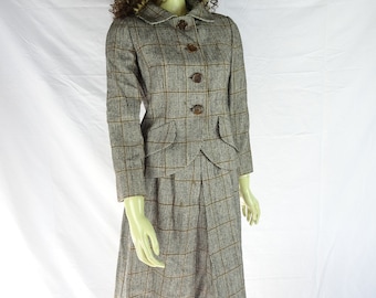May include: A brown and black plaid skirt suit with a collared jacket and four brown buttons. The jacket has two flap pockets.