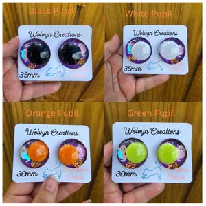 May include: Four pairs of round, decorative earrings with different colored pupils: black, white, orange, and green. Each pair is on a white card with the text "Wolvyn Creations", and "Pumpkin Patch". The black and white pairs are 35mm, and the orange and green pairs are 30mm.