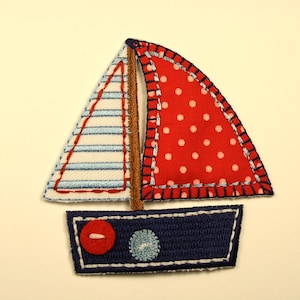 May include: A red and white sailboat applique with blue trim and a white and blue striped sail. The sailboat has a blue body with a red button and a white circle.