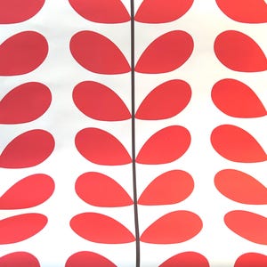 May include: Rolled wallpaper featuring a repeating pattern of red, teardrop-shaped designs on a white background. The design is divided by vertical black lines. The wallpaper is displayed on a striped upholstered chair.