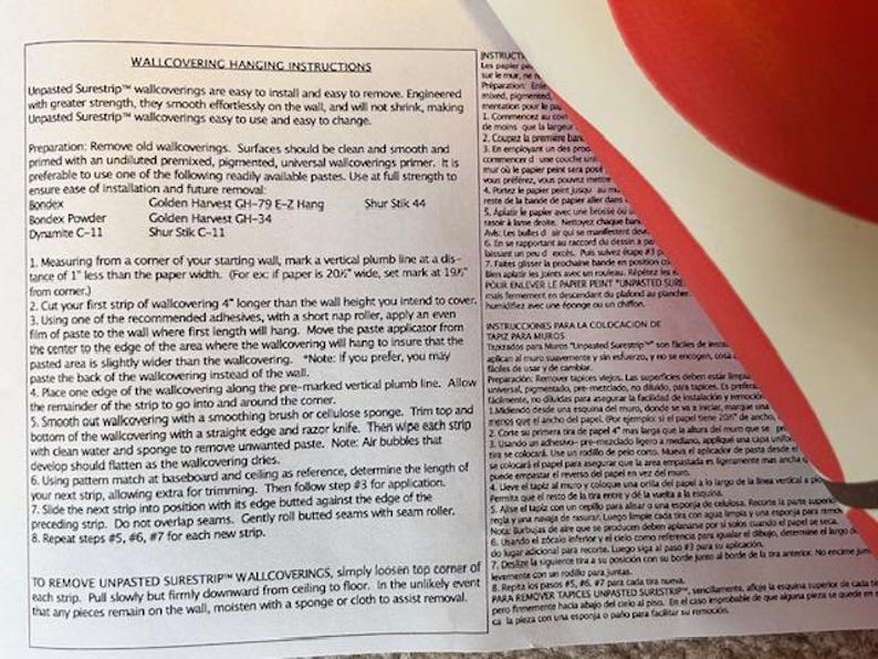 May include: Printed instructions for hanging wallpaper, with text in English and Spanish. The document details preparation, application, and removal of Surestrip wallcoverings. A red and white design is visible in the background.