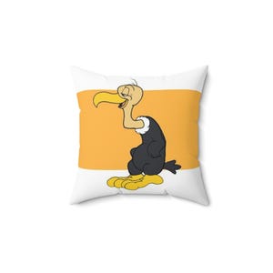 May include: Square pillow featuring a cartoon vulture character. The vulture has a yellow beak and feet, a black body, and a white neck ruff. The background is a horizontal orange stripe on a white background. The pillow is square and has a soft appearance.