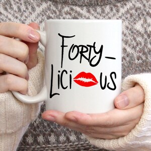 May include: White ceramic mug with black text that reads "Forty-licious" with a red lipstick kiss mark.