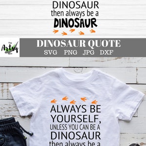 May include: A white t-shirt with a black graphic that reads "Always be yourself, unless you can be a dinosaur, then always be a dinosaur." The graphic is surrounded by orange dinosaur footprints.
