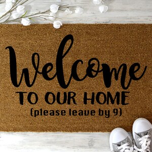 May include: A brown coir doormat with the text "Welcome to our home (please leave by 9)" in black lettering.