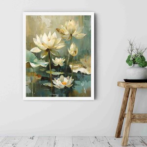 May include: A framed painting of white lotus flowers with yellow centers and green lily pads. The artwork has a soft, impressionistic style with a muted color palette of greens, blues, and creams. The painting is displayed on a white wall.
