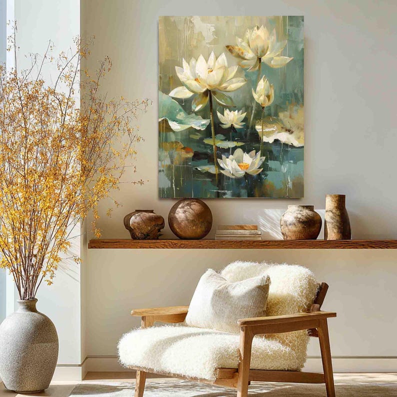 May include: An oil painting of white lotus flowers with yellow centers and green lily pads. The artwork hangs above a wooden shelf with decorative vases and a cozy armchair with a white cushion.