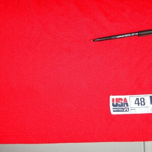May include: Red basketball jersey with a white Reebok patch that says "USA Basketball" and "48" on it.