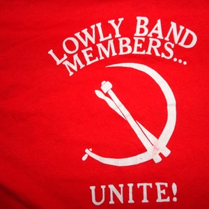 Könnte beinhalten: Rotes T-Shirt mit weißem Text, der "Lowly Band Members... Unite!" lautet, und einem weißen Symbol von Sichel und Hammer.