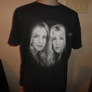 May include: Black t-shirt with a faded white image of two women's faces.