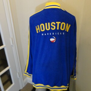May include: Blue and yellow vintage Houston Mavericks jacket with a basketball logo on the back.