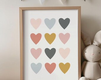 Puede incluir: Una impresión enmarcada con un fondo blanco y 15 corazones coloridos en varios tonos de rosa, azul, gris, rojo, amarillo y dorado. La impresión está en un marco de madera y está colgada en una pared.