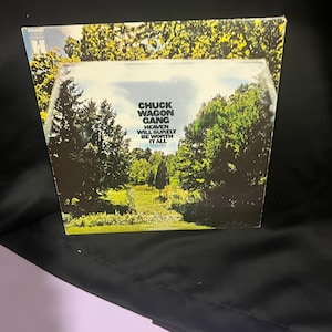 Könnte beinhalten: Ein Vintage-Vinyl-Plattencover mit einer grünen und braunen Waldszene, in der ein Weg durch die Bäume führt. Der Albumtitel lautet "Chuck Wagon Gang" und der Text "Heaven Will Surely Be Worth It All" ist unter dem Titel gedruckt.