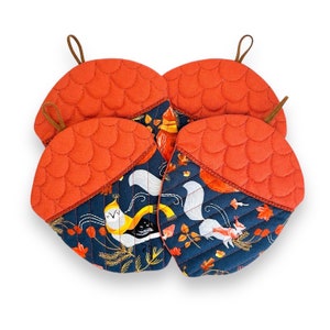 Puede incluir: Conjunto de cuatro agarraderas de olla en forma de bellota, de color rojo y azul, con estampado de animales del bosque. Las agarraderas tienen una textura acolchada y son perfectas para proteger tus manos de las superficies calientes.