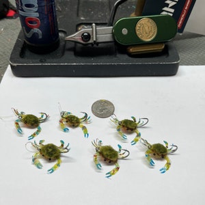May include: Six green and blue crab fly fishing lures with fuzzy bodies and clear plastic shells.