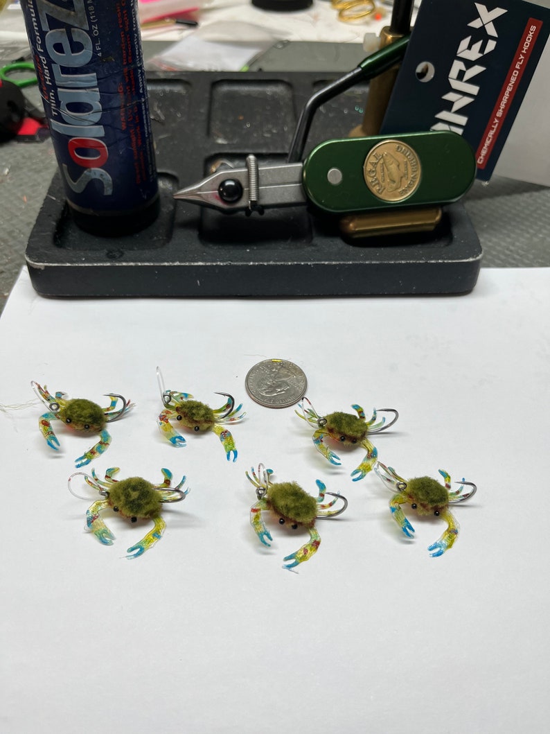 May include: Six green and blue crab fly fishing lures with fuzzy bodies and clear plastic shells.