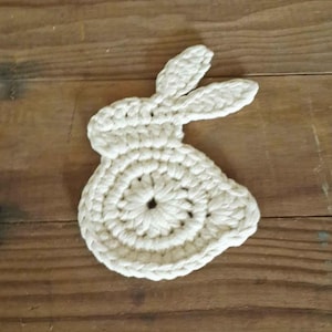 Peut inclure: Un lapin en crochet blanc avec un corps rond et de longues oreilles. Le lapin est fait d'un fil doux et texturé.