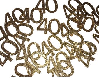 May include: Gold glitter confetti with the number 40 printed on each piece. The confetti is scattered on a white background.