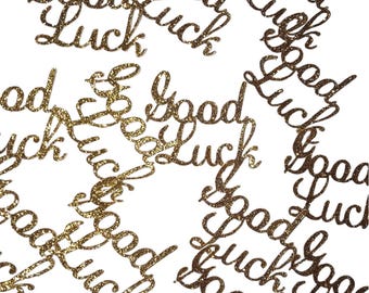 May include: Gold glitter confetti with the words "Good Luck" written on each piece.
