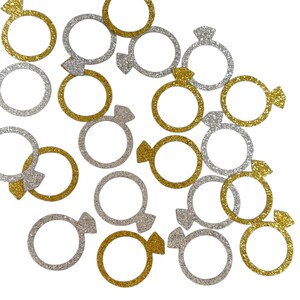 May include: Scattered gold and silver glitter ring confetti. The rings have a diamond design on the top.
