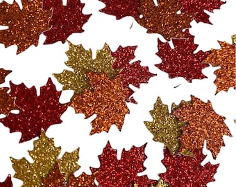 May include: Assortment of glitter maple leaves in red, gold, and orange colors. The leaves are scattered on a white background.