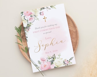 May include: A white card with pink and white flowers and a gold cross. The text reads: "Thank you for making my FIRST COMMUNION DAY so special! Love, Sophia May 9, 2030"