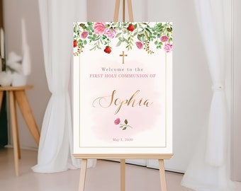 May include: A white welcome sign with a gold frame and pink watercolor background. The sign features a floral design with pink and red roses and green leaves. The text reads "Welcome to the First Holy Communion of Sophia May 1, 2030".