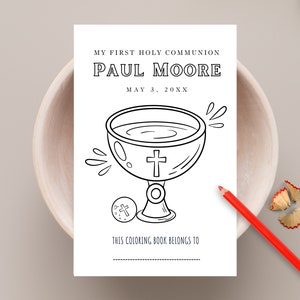 May include: A black and white colouring book page with a chalice and host. The text reads "My First Holy Communion Paul Moore May 3, 20XX This Colouring Book Belongs To".