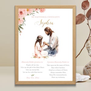 Puede incluir: Impresión enmarcada con una ilustración en acuarela de Jesús y una niña. La impresión incluye el nombre "Sophia" y texto sobre los convenios bautismales, con acentos florales rosas y verdes.
