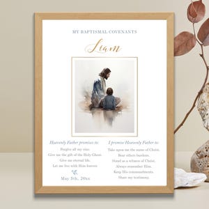 Puede incluir: Una impresión enmarcada con una imagen de acuarela de Jesús y un niño. La impresión incluye el nombre "Liam" en escritura dorada y texto sobre los convenios bautismales. El marco es de color marrón claro.