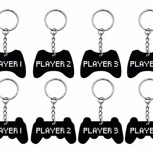 May include: Eight black metal keychains shaped like video game controllers with silver key rings and chains. The keychains are labelled "PLAYER 1", "PLAYER 2", "PLAYER 3", and "PLAYER 4".