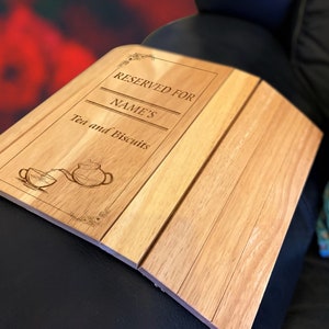 Könnte beinhalten: Ein Serviertablett aus hellem Holz mit der Gravur "RESERVED FOR NAME'S Tea and Biscuits". Das Tablett zeigt eine Illustration einer Teetasse und einer Teekanne. Das Tablett ist aus hellem Holz gefertigt.