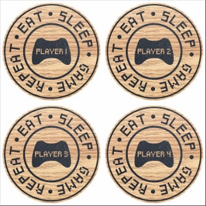 以下が含まれることがあります： 木目模様の茶色の丸いコースターが4つ。各コースターには、縁に「EAT. SLEEP. REPEAT. GAME」という黒い円が描かれています。円の内部には、黒いビデオゲームコントローラーが描かれており、各コースターに「PLAYER 1」、「PLAYER 2」、「PLAYER 3」、「PLAYER 4」の文字が書かれています。