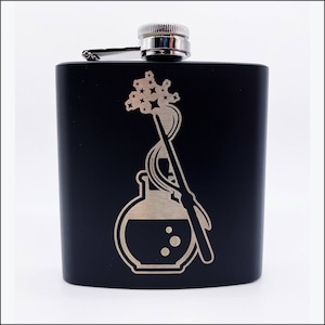 May include: Black stainless steel flask with a silver lid and a laser engraved design of a potion bottle and a magic wand with stars.
