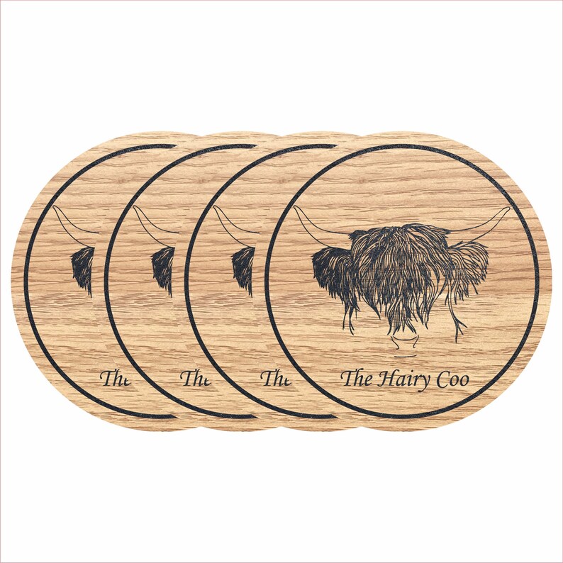 May include: Set of four round wooden coasters featuring a black and white line drawing of a Highland cow with the text "The Hairy Coo" on the bottom coaster.