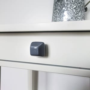 Puede incluir: Un cajón blanco con una perilla cuadrada de color gris oscuro.