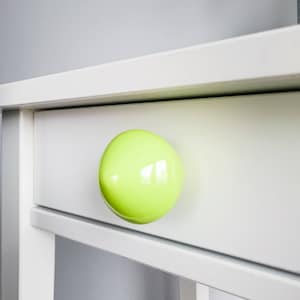 Puede incluir: Un cajón de armario blanco con una perilla redonda de color verde brillante.