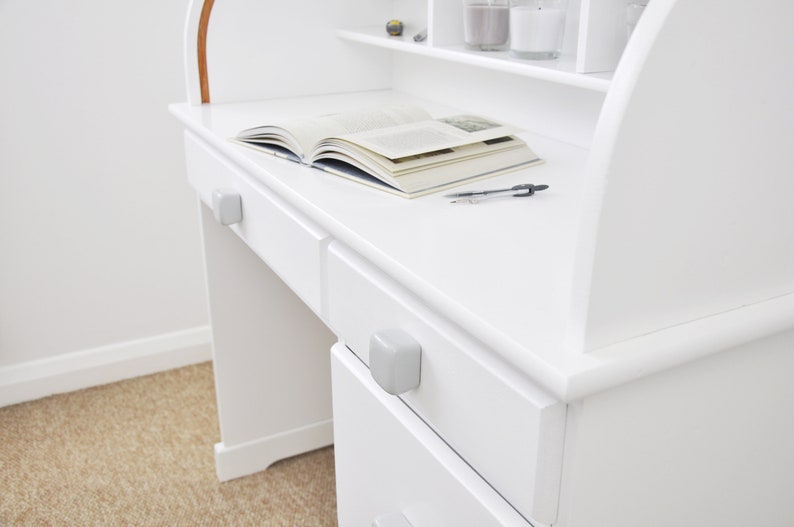Peut inclure: Bureau en bois blanc avec un dessus incurv&eacute; et deux tiroirs. Le bureau a un livre et un stylo sur la surface. Le bureau a une finition blanche.