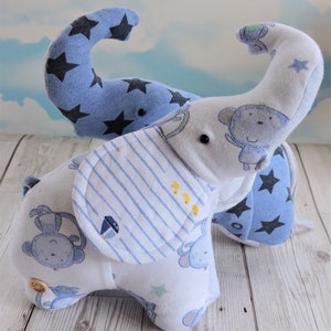 Pode incluir: Dois elefantes de pelúcia de tecido azul e branco. Um elefante tem um babador listrado azul e branco e o outro tem estrelas pretas em seu tecido azul. Ambos os elefantes têm um pequeno rosto de macaco em seu tecido.