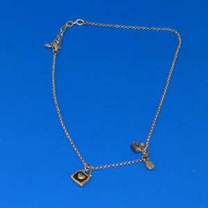 May include: A silver chain necklace with two charms. One charm is a small square with a heart inside, and the other charm is a small, round charm with a design.