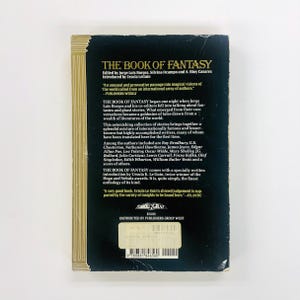 Może przedstawiać: Tylna okładka książki "The Book of Fantasy" autorstwa Jorge Luisa Borgesa, z tekstem o historiach i autorach antologii. Okładka jest czarna ze złotymi akcentami i zawiera metkę z ceną.