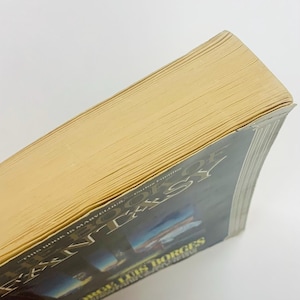 Może przedstawiać: Książka w twardej oprawie zatytułowana "The Book of Fantasy" autorstwa Jorge Luis Borges. Książka ma ciemną okładkę z białym tekstem i poż&oacute;łkłymi krawędziami stron. Książka jest ustawiona pod kątem, pokazując strony i okładkę.