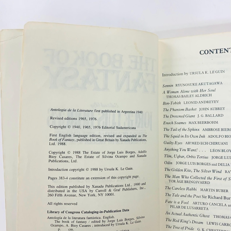 Może przedstawiać: Otwarta strona książki z tekstem. Lewa strona zawiera informacje o prawach autorskich do "The Book of Fantasy", w tym daty publikacji i szczeg&oacute;ły wydawcy. Prawa strona zawiera spis treści z autorami i tytułami.