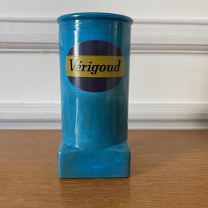 Può includere: Un vaso in ceramica blu con un logo giallo e nero che dice "Vérigood".