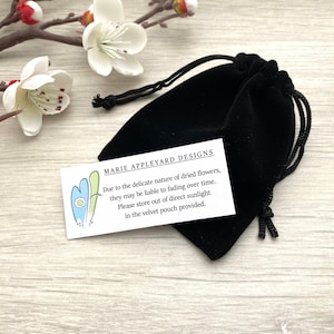 May include: A black velvet pouch with a white card that reads "MARIE APPLEYARD DESIGNS Due to the delicate nature of dried flowers, they may be liable to fading over time. Please store out of direct sunlight in the velvet pouch provided."
