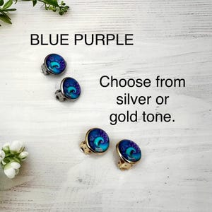 May include: Four round stud earrings featuring a blue and purple spiral pattern. Two earrings have silver-tone metal settings and two have gold-tone metal settings. The text BLUE PURPLE and Choose from silver or gold tone. is visible in the image.