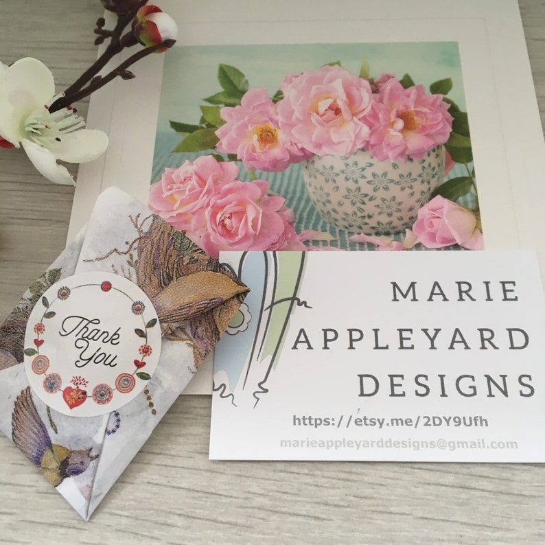 May include: A small gift packet wrapped in patterned paper with a circular Thank You sticker, accompanied by a business card for Marie Appleyard Designs featuring a URL and email address, set against a floral print card with pink roses.