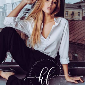May include: A woman wearing a white button-down shirt and black trousers sits by a window. The text "Style Blogger | Katie French | Style Blogger" is written in a circle around the letters "kf".