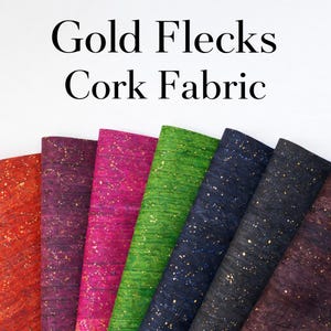 Könnte beinhalten: Eine Auswahl an farbigen Korkstoffrollen mit Goldflocken. Die Rollen sind in den Farben Rot, Lila, Pink, Grün, Blau und Schwarz gehalten. Der Text "Gold Flecks Cork Fabric" befindet sich oben im Bild.
